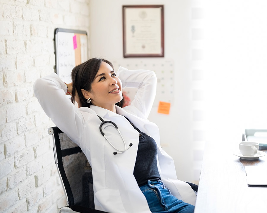 Woman medical professional leaning back in office chair and smiling