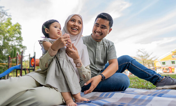 Happy family sitting together on a blanket at the park.