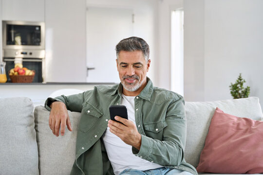 Mature man using his phone while sitting on a couch