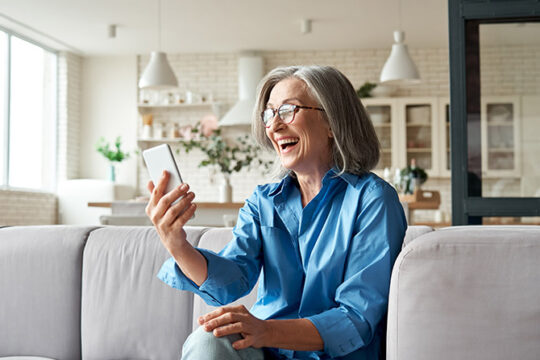 Mature woman in blue shirt using her phone