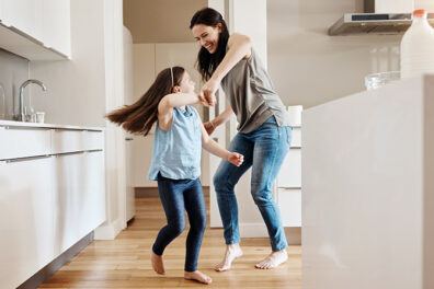 Mother daughter in their kitchen dancing