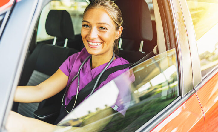 Female nurse in purple scrubs driving a vehicle