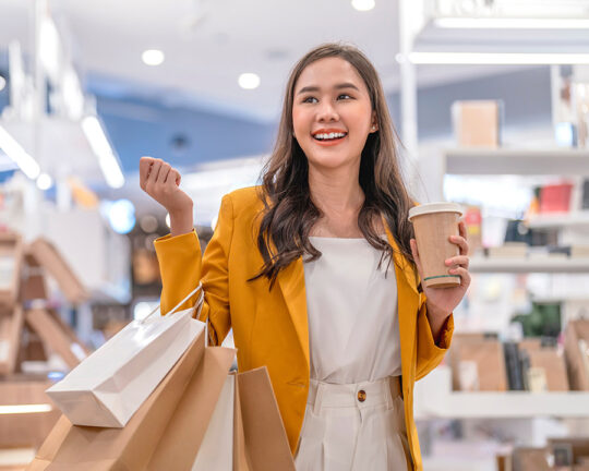Woman in yellow blazer holding lots of shopping bags