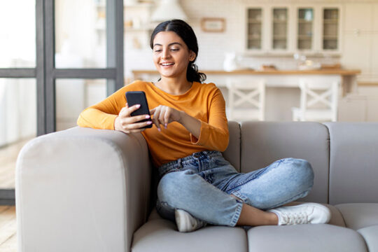 Young woman using her phone while sitting on the couch